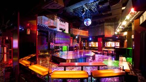 Zona de bar con escenario, asientos y una bola de discoteca.