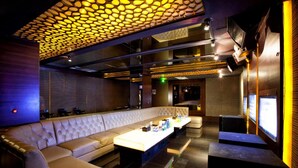 Un salón moderno con un largo banco acolchado y un techo alto con una lámpara geométrica única.