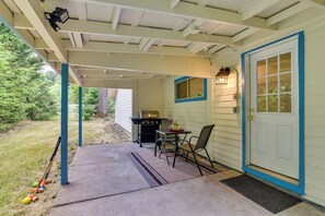 Eine überdachte Veranda mit Grill, Tisch und Stühlen.