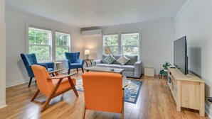 A modern living room with a sofa, two blue armchairs, a coffee table, and a TV on a wooden stand. - Downtown Home w/ Patio - Walk to Shops & Dining! (Stevenson)