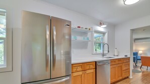 A modern kitchen with stainless steel appliances, wooden cabinets, and a window providing natural light. - Downtown Home w/ Patio - Walk to Shops & Dining! (Stevenson)