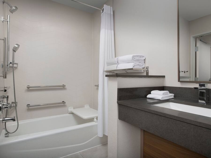 A modern bathroom with a bathtub, shower, and vanity with a mirror.