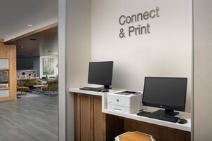 Un espacio de trabajo con dos monitores, una impresora y un teclado.