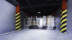A spacious indoor area with a high ceiling, concrete floor, and yellow and black striped safety barriers. - SUPER OYO Flagship 3688 Pot Art (Surabaya)