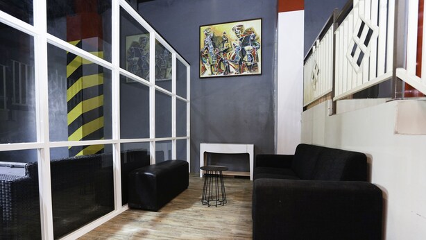 A modern living room with a black sofa, a small table, and a painting on the wall. - SUPER OYO Flagship 3688 Pot Art (Surabaya)