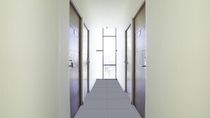 A narrow hallway with doors on both sides leading to a bright exit. - SUPER OYO Flagship 3688 Pot Art (Surabaya)