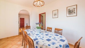 Comedor con una mesa cubierta por un mantel azul y blanco estampado, rodeado de sillas de madera.