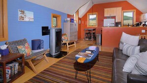 A living room with a sofa, a television, and a coffee table. There is a kitchen area with a refrigerator and a window. - The Surf Shack, On shuttle route, EV charger (Crested Butte)