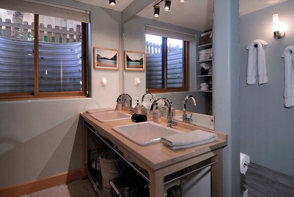 A bathroom with two sinks, a mirror, and a window with a view of a fence and trees. - The Surf Shack, On shuttle route, EV charger (Crested Butte)