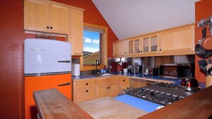 A kitchen with wooden cabinets, a refrigerator, a stove, and various appliances. - The Surf Shack, On shuttle route, EV charger (Crested Butte)