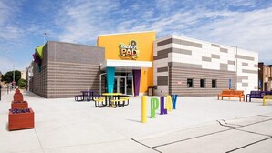 A children's museum with a Play sign, picnic tables, and benches.