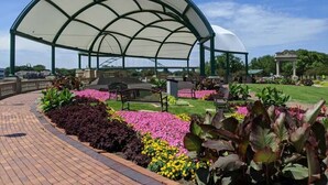 A covered pavilion with a curved roof, surrounded by a brick pathway and colorful flower beds. - avid hotel Sioux City - Downtown by IHG (Sioux City)