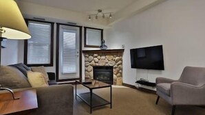 Ein Wohnzimmer mit Kamin, Fernseher und einer Couch.