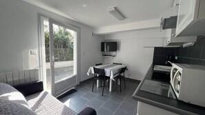 A compact kitchen with a dining area, a TV mounted above the counter, and a sliding glass door leading to an outdoor area.
