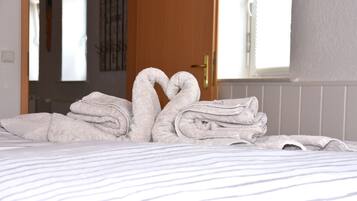 A bed with neatly folded towels arranged in a heart shape.