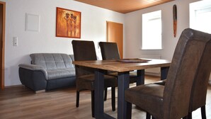 Un coin repas avec une table et des chaises en bois, un canapé gris et un tableau au mur.