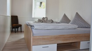 Une chambre à coucher avec un lit en bois, une fenêtre et une chaise.