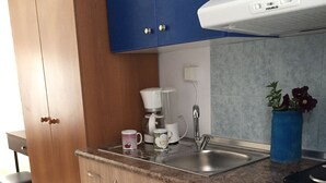 Una cucina compatta con lavello, macchina del caffè e un piccolo frigorifero.