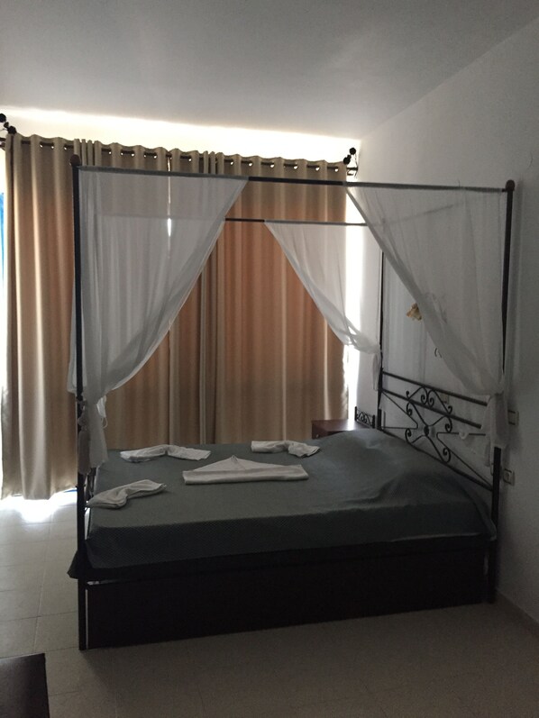 Una cama con dosel y cuatro columnas, una mesita de noche y una mesilla.