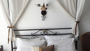 Un letto a baldacchino, un elemento decorativo a parete e una testiera.