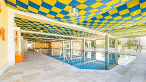 An indoor swimming pool with a checkered ceiling, clear glass walls, and a tiled floor. - FeWo Längl - modern "Alpenguck" apartment with pool and sauna in the Allgäu (Scheidegg)