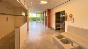 A hotel corridor with a reception desk, a waiting area with a bench, and a glass door leading to a garden. - FeWo Längl - modern "Alpenguck" apartment with pool and sauna in the Allgäu (Scheidegg)