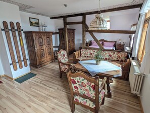 Una habitación rústica con muebles de madera, una mesa de comedor y un banco tapizado con flores.