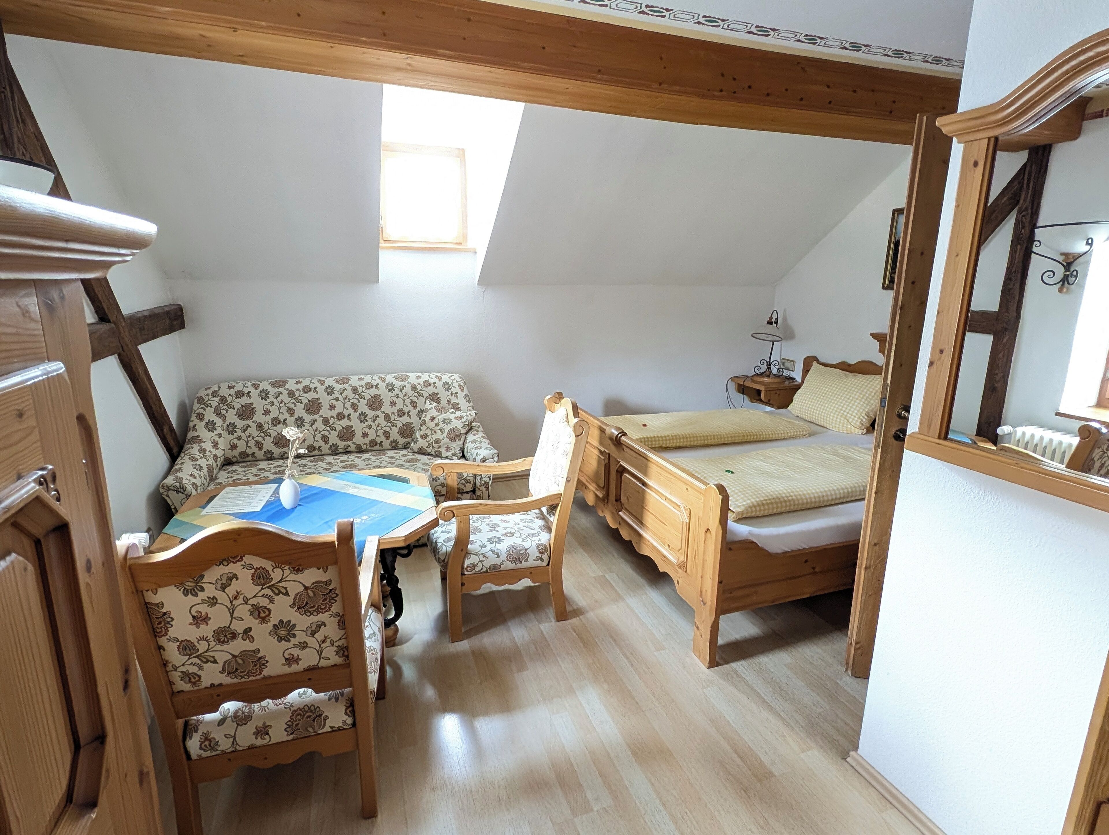 Une chambre confortable située sous les toits, avec un lit en bois, un canapé et une table à manger.