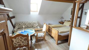 Une chambre confortable située sous les toits, avec un lit en bois, un canapé et une table à manger.