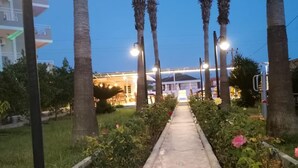 A pathway lined with palm trees leading to a building with illuminated windows. - Side Ozgurhan Hotel (Manavgat)