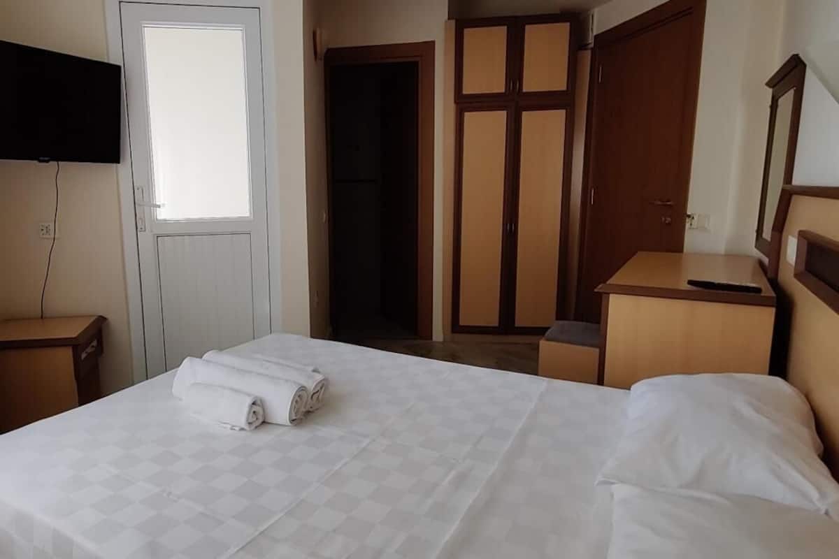 Une chambre d’hôtel avec un lit, un téléviseur fixé au mur, une armoire et un miroir.