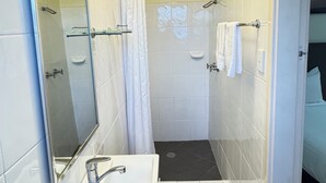 A bathroom with a shower, a sink, and a mirror. - Taree Motor Inn (Taree)