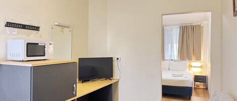 Ein kleines Hotelzimmer mit Küchenzeile, Schreibtisch, Bett und Sitzecke.