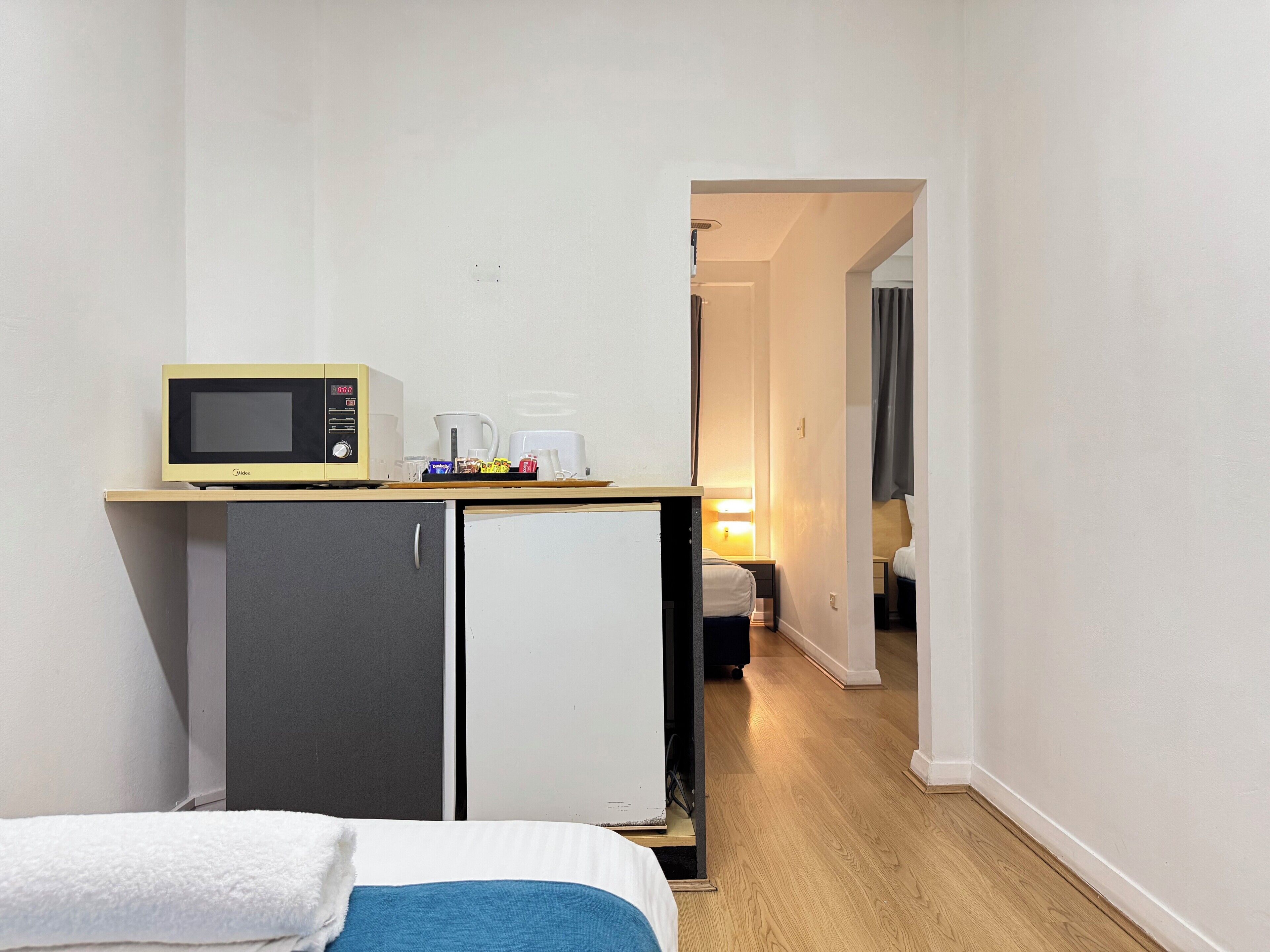Ein kleines Hotelzimmer mit Küchenzeile, einem Bett und einem kompakten Badezimmer.