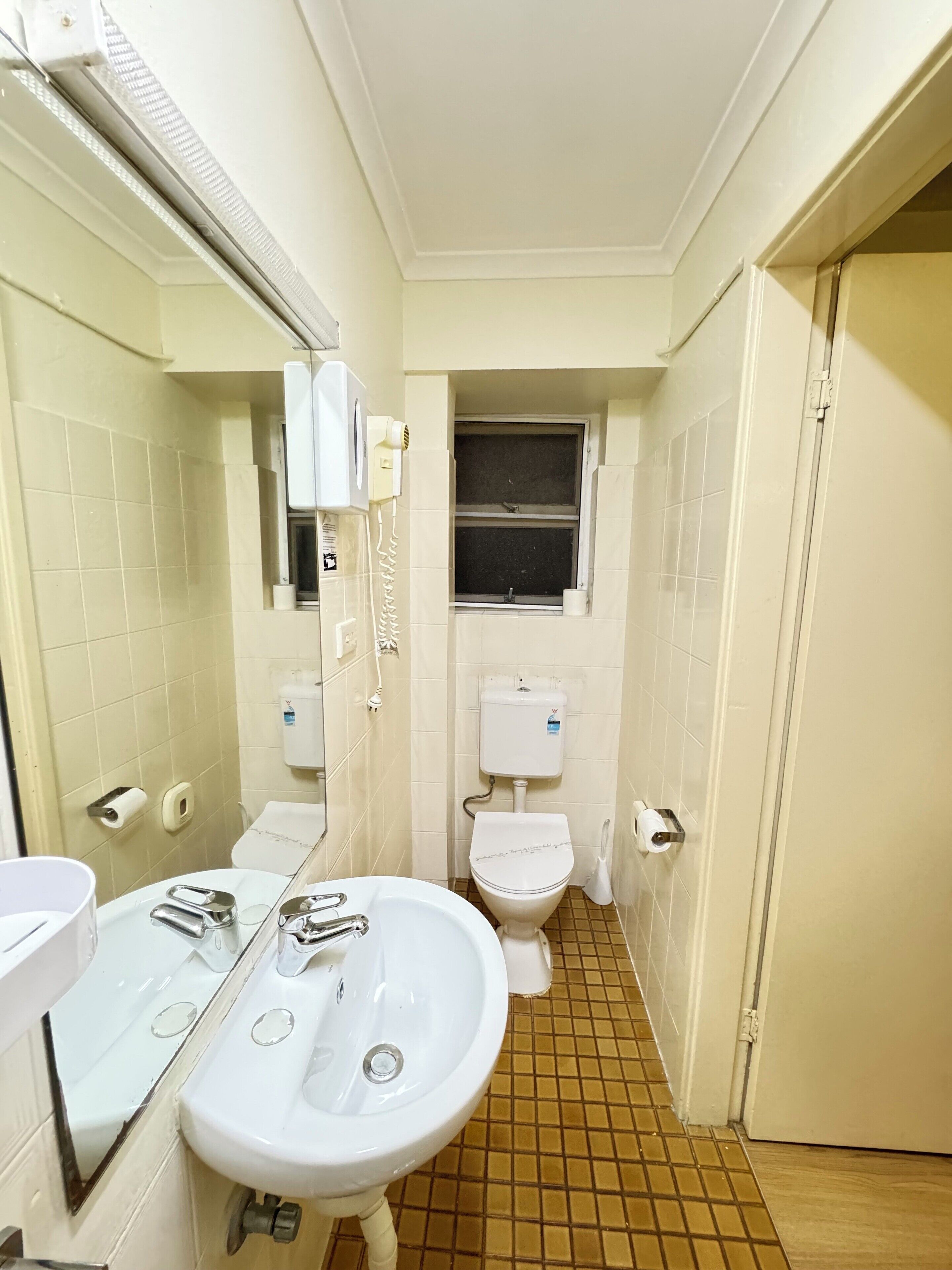 Un baño pequeño y limpio con un lavamanos, espejo y retrete blancos.