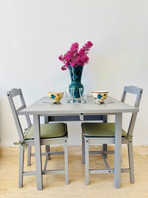 Una mesa de comedor con dos sillas, un florero con flores rosas y dos cuencos con diseño de taza de café.