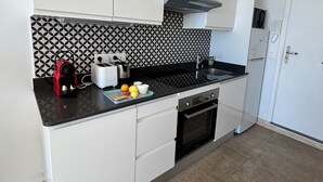 Una cocina moderna con armarios blancos, salpicadero blanco y negro, una cafetera y un tostador.