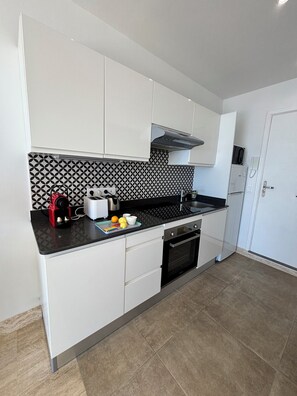 A modern kitchen with white cabinets, a black and white backsplash, a coffee maker, and a toaster.