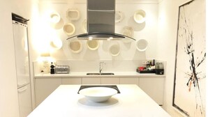A modern kitchen with a white countertop, a central island with a bowl, a toaster, and a sink.