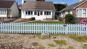 A residential house with a white exterior, a front porch, and a gravel driveway. - Atlantic Retreat - 5 minute stroll from Crooklets Beach (Bude)