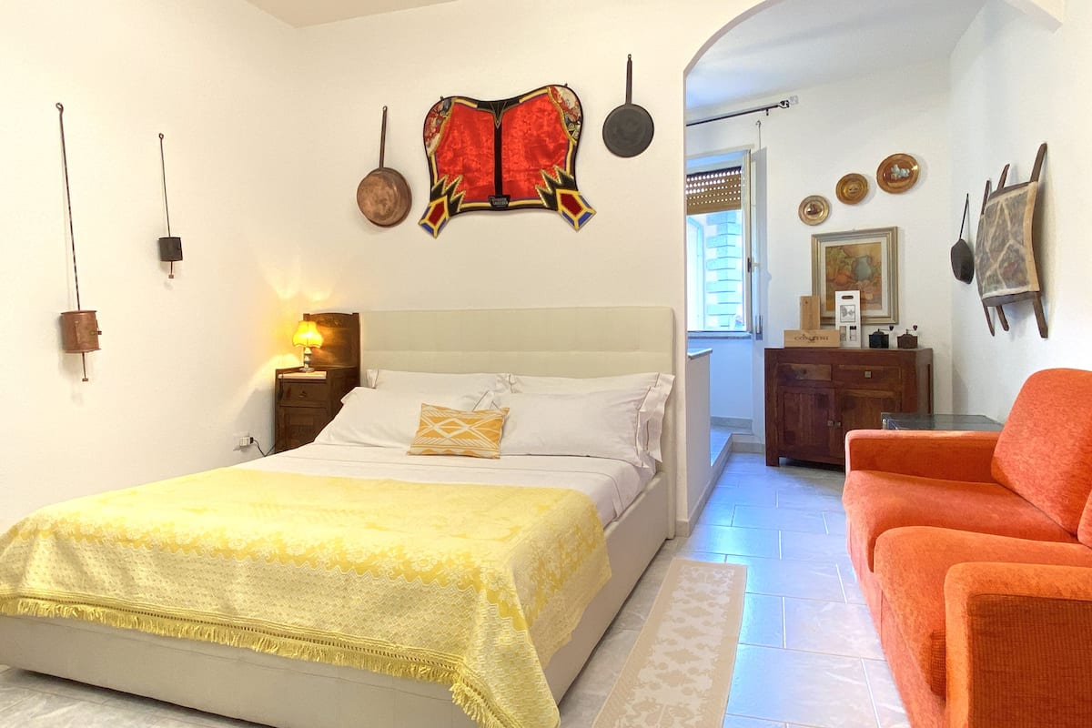 A bedroom with a bed, a nightstand, a lamp, a dresser, and a chair.