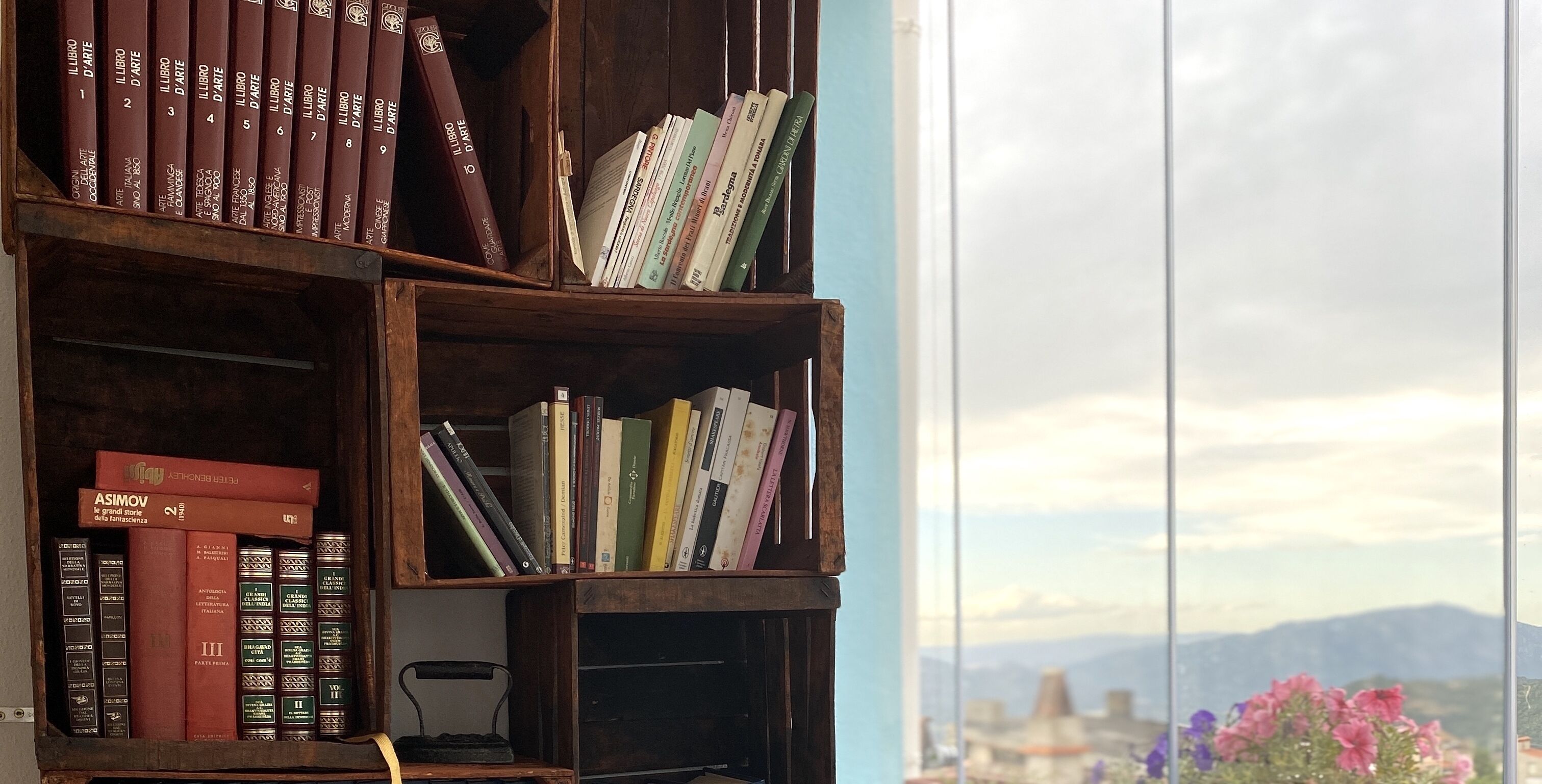 Ein Bücherregal mit Büchern und einer Schreibmaschine, neben einem Fenster mit Blick auf die Stadtlandschaft.