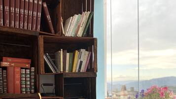 Ein Bücherregal mit Büchern und einer Schreibmaschine, neben einem Fenster mit Blick auf die Stadtlandschaft.