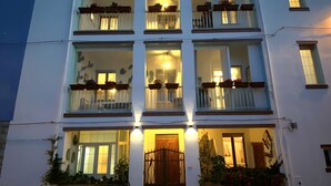 A multi-story building with balconies, a central entrance, and potted plants. - Canduleri (Orgosolo)