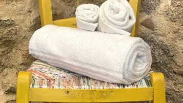 Una silla amarilla con toallas blancas enrolladas y una toalla colorida.
