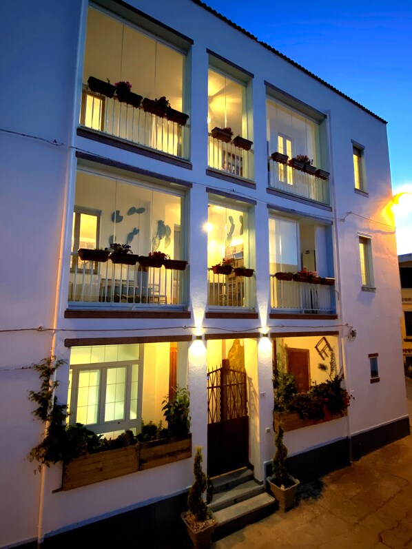 A multi-story hotel with balconies, large windows, and outdoor plants.