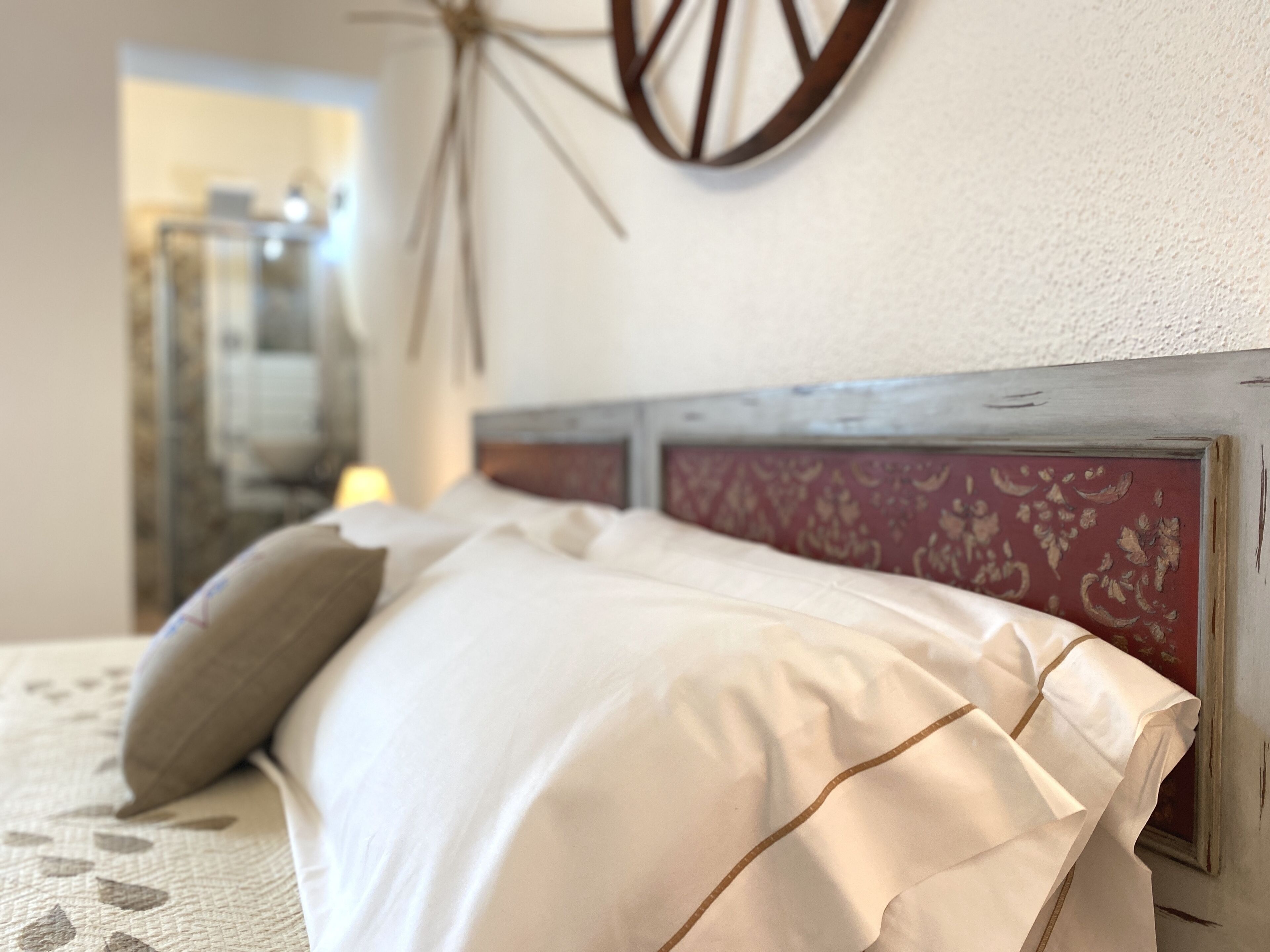 A bed with white linens and a headboard with a floral pattern.