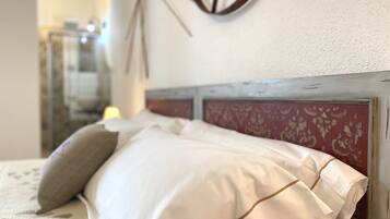 A bed with white linens and a headboard with a floral pattern.