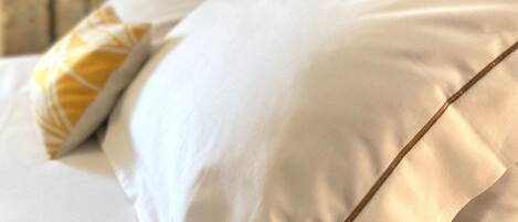 A neatly made bed with white linens and a wooden headboard.