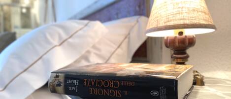 Una mesita de noche con una lámpara y un libro titulado "La Divina Comedia" de Dante Alighieri.